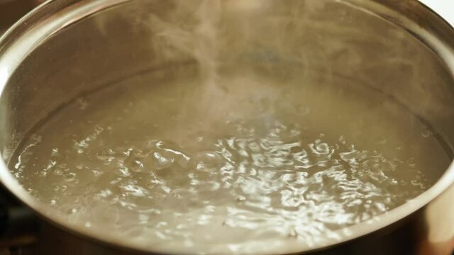 salting boiling water in stainless steel pot - close-up slowed down four times.