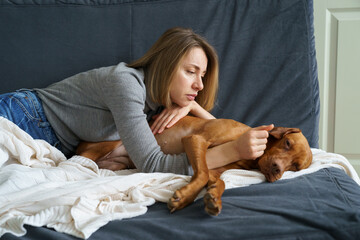 Worried woman taking care of weakening old dog at home. Poor animal suffer from stomach ache need...