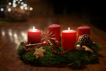 Obraz na płótnie Canvas Second Advent - decorated Advent wreath from fir branches with red burning candles on a wooden table in the time before Christmas, festive bokeh in the warm dark background, copy space, selected focus