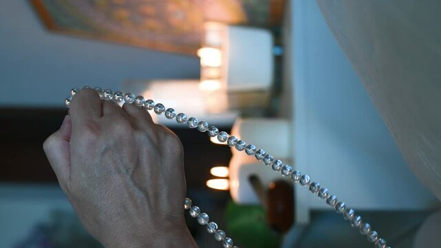 vertical video. a man sits in a lotus position. close-up of hands fingering rosary. isoteric theme. High quality 4k footage