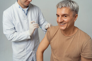 A man gets an injection of flu vaccination at the clinic. Doctor of Medical Sciences professor...