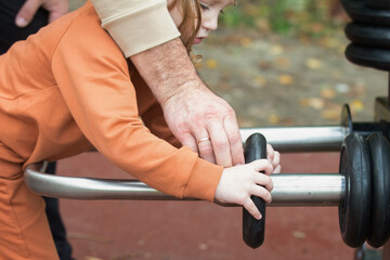 A man and a child on the machine adjust the weight and discs. Active, healthy walks on the city streets