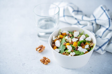 Roasted pumpkin avocado arugula goat cheese salad in a plate