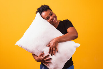 Afro mature woman with pillow on yellow background with space for text. Sleep and comfort concept