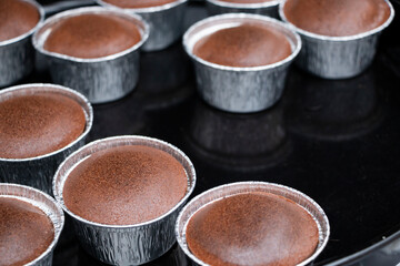 Obraz na płótnie Canvas Freshly baked chocolate souffles dusted with powdered sugar. French traditional delicious chocolate souffle on baking tray.