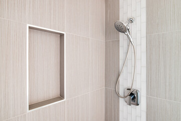 A detail shot of a beautifully tiled shower with brown large tiles, white subway tiles, and a shelf...