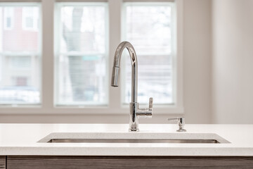Detail shot of a kitchen sink with chrome hardware surrounded by white granite.