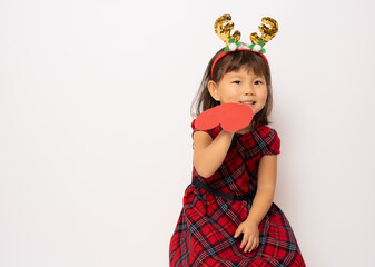 Beautiful little asian girl in santa hat showing a red heart isolated over white background.