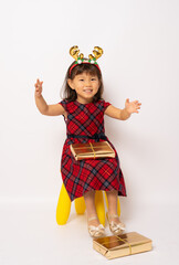 Cute smiling little asian girl in santa hat sitting with gift box isolated over white background.