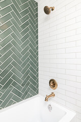 A green single herringbone and white subway tile shower with gold hardware in a luxury home.