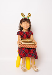 Happy little asian girl in santa hat holding gift boxes isolated over white background.
