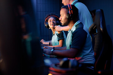 Young man, cybersport gamer, helping female friend while participating as one team in esports tournament in gaming club © Yaroslav Astakhov