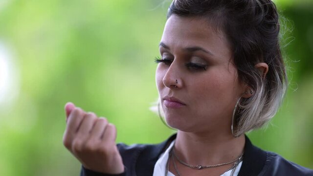 Nervous young woman biting nails outside