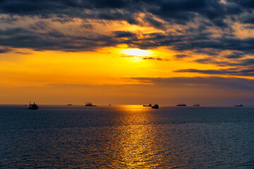 Beautiful sunset in the sea and ships. The sun shines through the clouds and is reflected in the waves