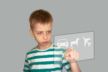 A boy with a dissatisfied face chooses a toy on an interactive scoreboard. Isolate on a gray background. Negative emotion of the child.