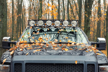 Close-up detail view of custom made roof rack bar with extra headlight mounted on roof of heavy duty pick up suv car against foggy autumn forest. Fallen leaves vehicle windshield. Fall weather drive © Kyryl Gorlov