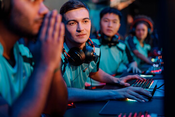 Male concentrated esports player looking at PC monitor in gaming club