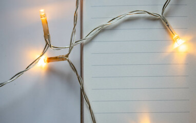 Fototapeta na wymiar christmas lights on an empty notebook page