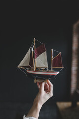 Fototapeta na wymiar beautiful toy wooden ship in hand on a dark background close up indoors close-up