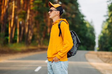 Happy male traveler with backpack traveling on the road along the forest trail. Camping