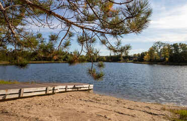 Fototapeta na wymiar small lake with a sand beach and a dock