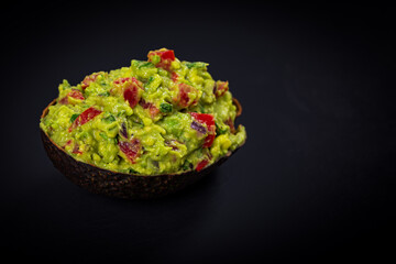 Guacamole Dip in Halves of Avocado Skins on Black Background with Copy Space. Selective focus.