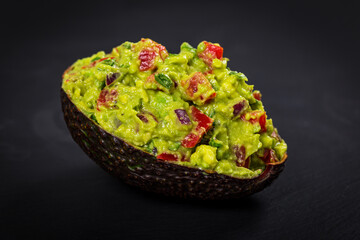 Guacamole Dip in Halves of Avocado Skins on Black Background with Copy Space. Selective focus.