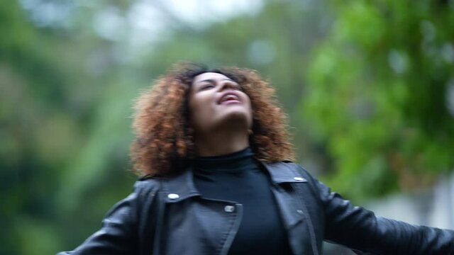 Young black woman feeling the rain outside spinning feeling free