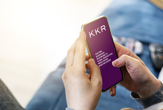Young woman using her mobile phone with the application of the American investment company KKR