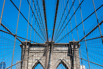 American flag on the Brooklyn Bridge against a blue sky