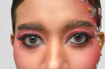 Obraz premium Woman wearing pink makeup and embellishments on her face