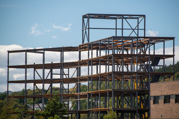The exterior construction of a large multi-story high-rise building is being erected from steel panels, iron forms, metal beams, and an industrial engineered layout. It is a  prefab structure. 