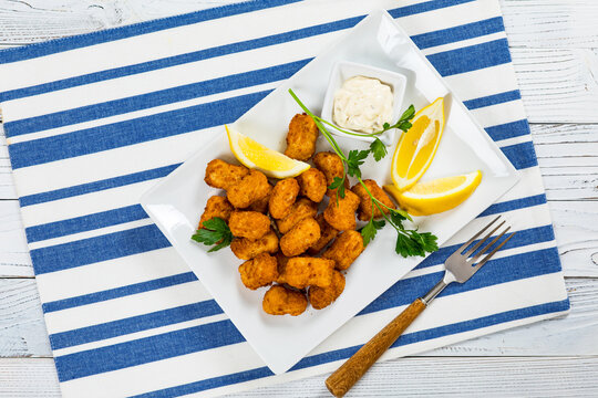 Crispy Fish Bites Snack Size. Deep Fried Codfish Fish Fingers and Chips with Tartar Dipping Sauce on a wooden board. Selective focus.