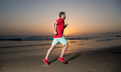 morning workout activity. healthy man running on sunrise beach. energetic summer.