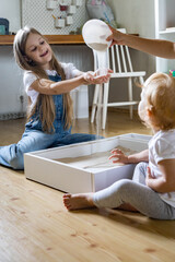Happy family mother and kids playing home kinetic sandbox development ecological materials toys