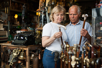 Elderly man and woman examine rare walking stick on flea market. High quality photo