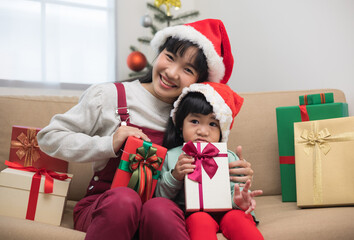 Obraz na płótnie Canvas Cute Asian family Mother and son giving the present gift box each other. In the christmas eve festival. Mom and little child dressing christmas theme sitting on sofa with happy moment new year's day