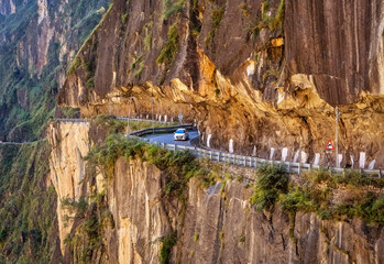 Tourist car driving on dangerous mountain road from Sarahan to Sangla at Himachal Pradesh, India