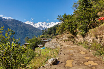 Fototapeta na wymiar Unpaved village road with Himalaya mountain snow peaks at Kalpa Himachal Pradesh, India