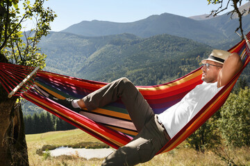Obraz na płótnie Canvas Man resting in hammock outdoors on sunny day