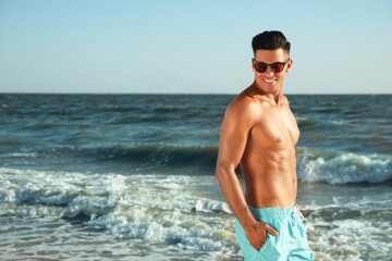 Fototapeta na wymiar Handsome man with attractive body on beach. Space for text