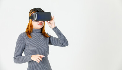 Studio shot of Asian young dyed hair female model in gray turtleneck dress wears artificial intelligence virtual reality vr video game goggles headset watching 3d console gameplay on white background