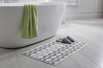 Stylish mat with slippers on floor near tub in bathroom. Interior design - obrazy, fototapety, plakaty
