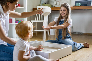 Happy family mother and kids playing home kinetic sandbox development ecological materials toys