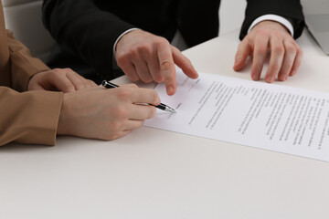 Businesspeople signing contract at white table, closeup of hands