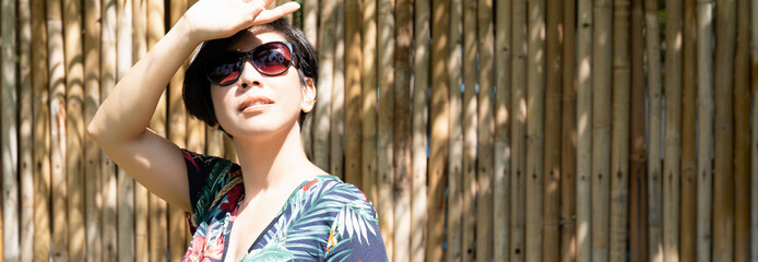 Banner of beautiful stylish Asian woman wear 100% UV light eyes protection sunglasses, raise hand...