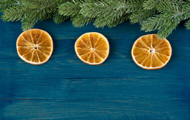 Fototapeta na wymiar New Year's composition of dried orange slices and artificial spruce branches on a blue wooden background with a place for the text top view