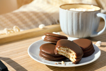 Tasty choco pies and cup of hot drink on wooden tray