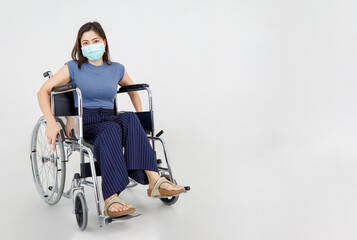 Obraz na płótnie Canvas Asian woman patient sitting on hospital wheelchair as disabled people and wearing hygiene face mask to protect covid-19 disease infection during medical treatment of mobility injury