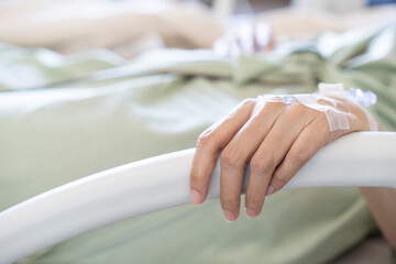 Focus on the hand of a woman patient in hospital ward and lie down handle the rail bed with hope on...